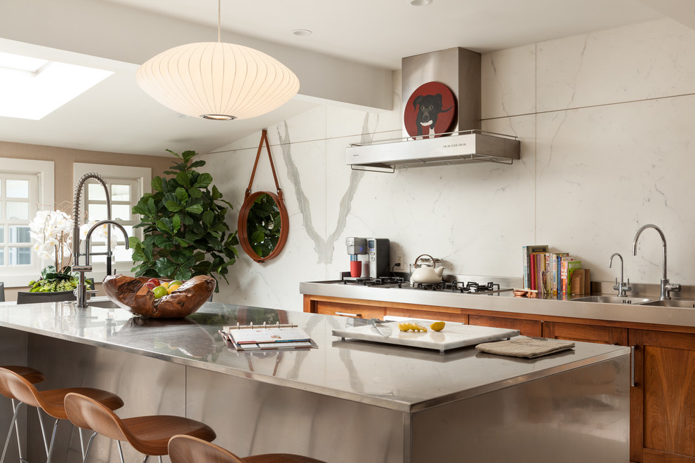 Modern inredning av ett mellanstort kök, med en integrerad diskho, skåp i shakerstil, skåp i rostfritt stål, bänkskiva i rostfritt stål, vitt stänkskydd, stänkskydd i sten, rostfria vitvaror, målat trägolv och en köksö