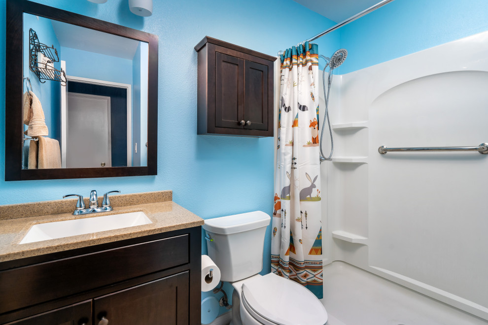 This is an example of a small transitional 3/4 bathroom in Los Angeles with recessed-panel cabinets, brown cabinets, an alcove shower, a two-piece toilet, beige tile, blue walls, vinyl floors, an undermount sink, engineered quartz benchtops, beige floor, a shower curtain and brown benchtops.