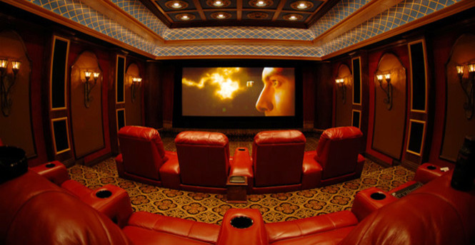 This is an example of a large midcentury enclosed home theatre in New York with red walls, carpet, a projector screen and brown floor.