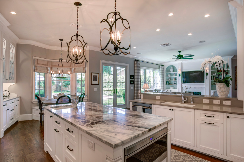 Inspiration for a large traditional kitchen in Orlando with an undermount sink, recessed-panel cabinets, white cabinets, quartz benchtops, beige splashback, porcelain splashback, stainless steel appliances, medium hardwood floors, with island and brown floor.