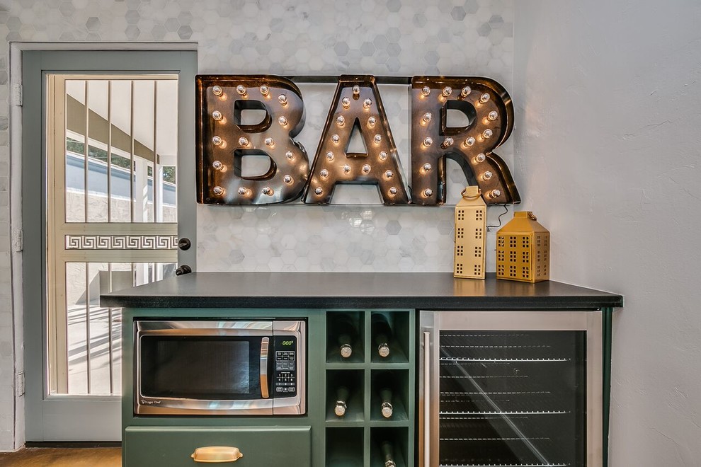 Mid-sized transitional single-wall wet bar in Phoenix with green cabinets, grey splashback, marble splashback, concrete floors and brown floor.