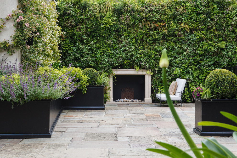 Traditional courtyard patio in London with a vertical garden and natural stone pavers.