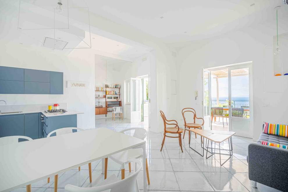 Стильный дизайн: огромная гостиная-столовая в средиземноморском стиле с белыми стенами, полом из керамической плитки и бирюзовым полом - последний тренд