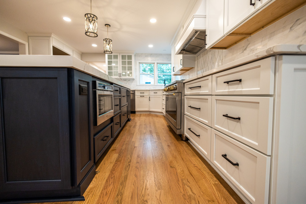 Example of a large transitional l-shaped light wood floor and brown floor eat-in kitchen design in Baltimore with an undermount sink, shaker cabinets, white cabinets, quartz countertops, white backsplash, marble backsplash, stainless steel appliances, an island and white countertops