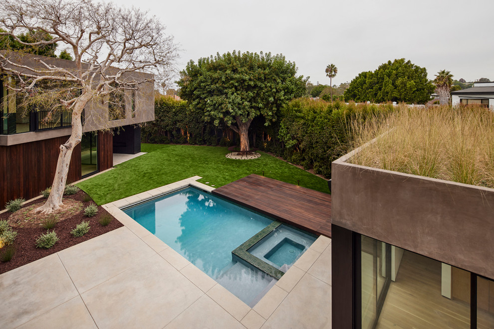 Photo of an expansive modern backyard partial sun xeriscape for winter in Los Angeles with with privacy feature, concrete pavers and a wood fence.