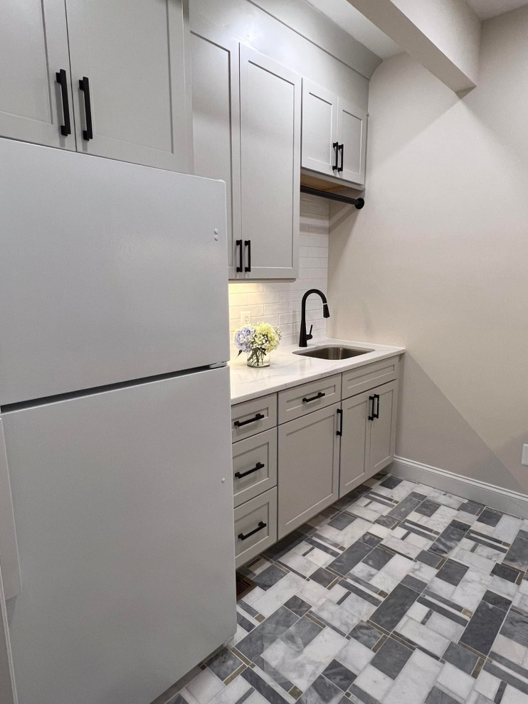 Foto på en mellanstor funkis vita parallell tvättstuga enbart för tvätt, med en undermonterad diskho, skåp i shakerstil, grå skåp, bänkskiva i kvarts, vitt stänkskydd, stänkskydd i cementkakel, grå väggar, marmorgolv, en tvättmaskin och torktumlare bredvid varandra och vitt golv
