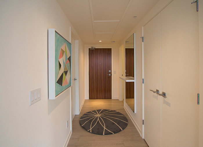 Photo of a small modern entry hall in Calgary with white walls, light hardwood floors, a single front door and a medium wood front door.