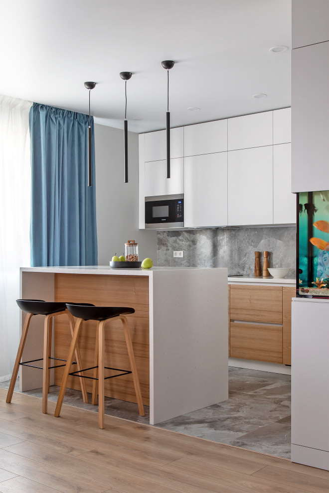 Inspiration for a mid-sized contemporary single-wall open plan kitchen in Other with an integrated sink, flat-panel cabinets, white cabinets, solid surface benchtops, grey splashback, porcelain splashback, stainless steel appliances, porcelain floors, with island, grey floor and beige benchtop.
