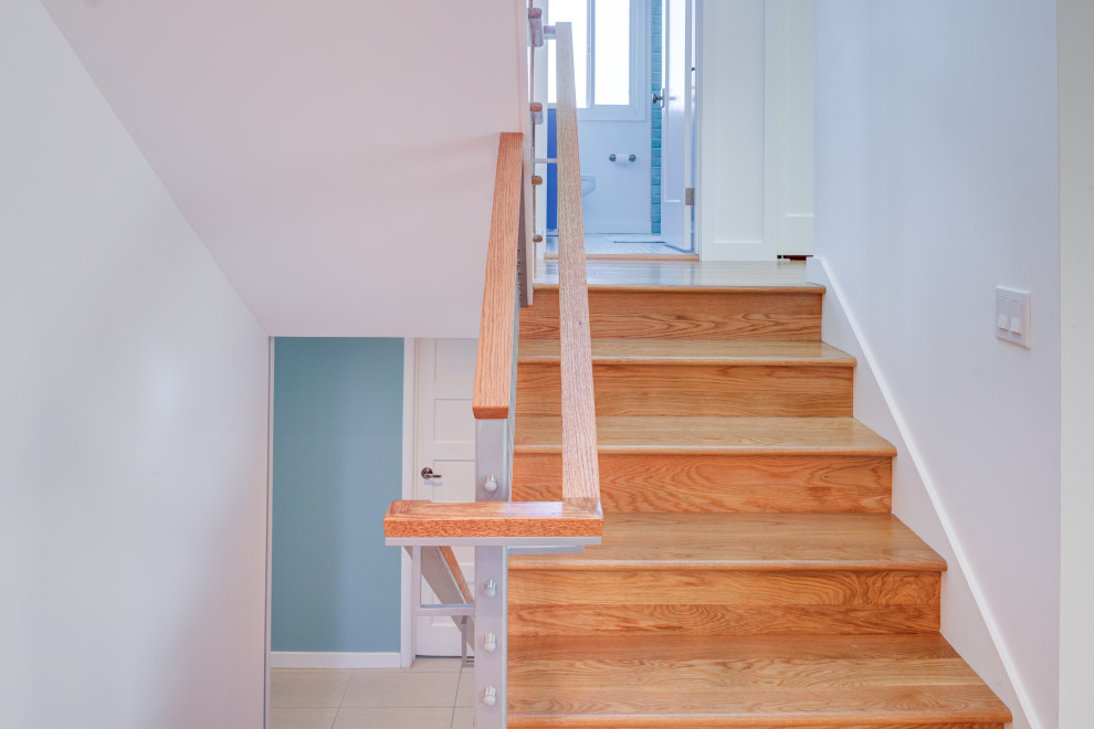 Imagen de escalera en U actual con escalones de madera, contrahuellas de madera y barandilla de varios materiales