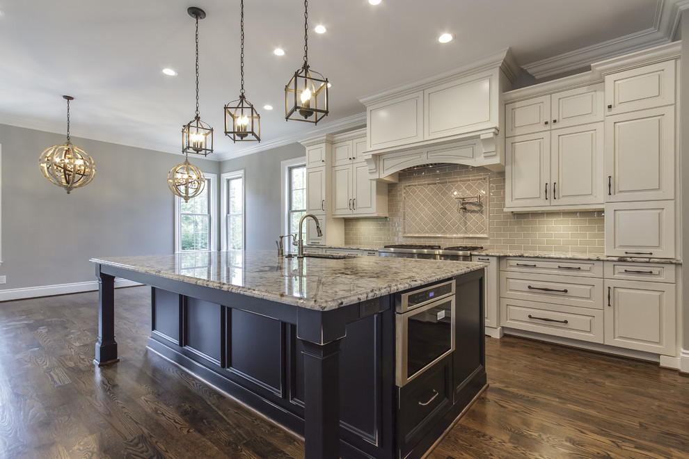 Example of a mid-sized transitional medium tone wood floor and brown floor open concept kitchen design with an undermount sink, raised-panel cabinets, black cabinets, granite countertops, gray backsplash, stainless steel appliances, an island and multicolored countertops