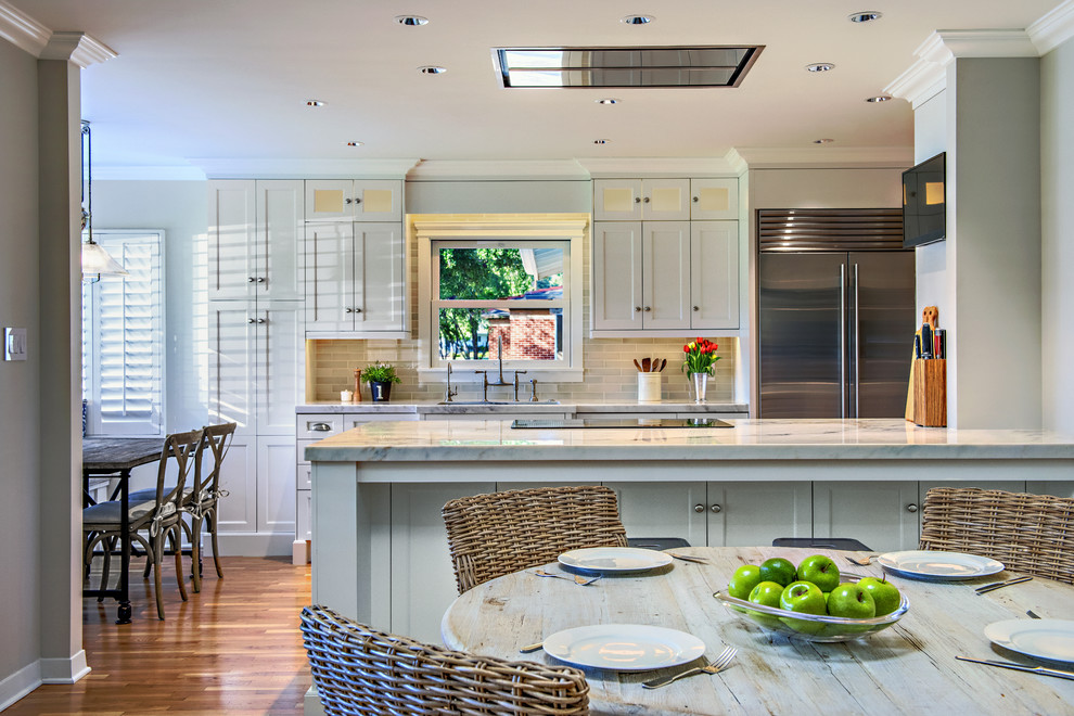 Enclosed kitchen - mid-sized transitional single-wall medium tone wood floor enclosed kitchen idea in Phoenix with an undermount sink, shaker cabinets, white cabinets, marble countertops, gray backsplash, subway tile backsplash, stainless steel appliances and an island