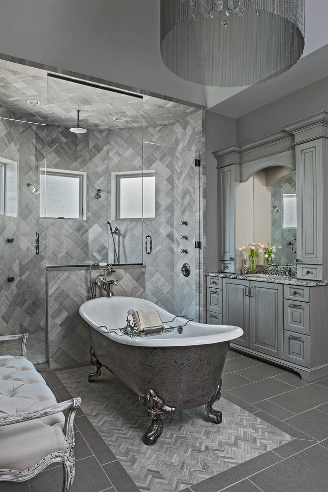 Master bathroom in Detroit with raised-panel cabinets, grey cabinets, a claw-foot tub, a curbless shower, gray tile and a hinged shower door.
