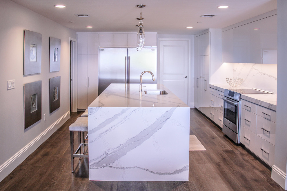 Inspiration for a large modern eat-in kitchen in Tampa with an undermount sink, white cabinets, quartz benchtops, stainless steel appliances, with island, flat-panel cabinets, white splashback, stone slab splashback, medium hardwood floors and brown floor.
