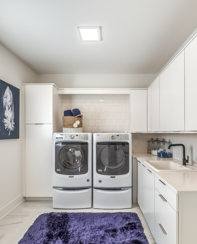 Large contemporary l-shaped dedicated laundry room in Other with a drop-in sink, flat-panel cabinets, white cabinets, quartz benchtops, white walls, ceramic floors, a side-by-side washer and dryer, white floor and white benchtop.