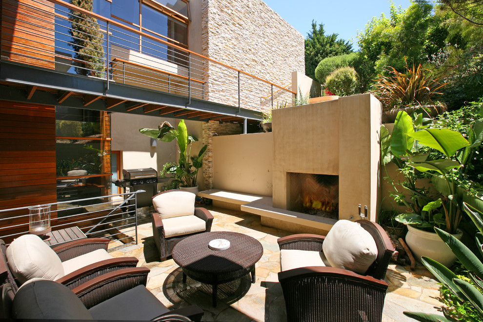 Design ideas for a contemporary patio in Orange County with natural stone pavers and a fire feature.