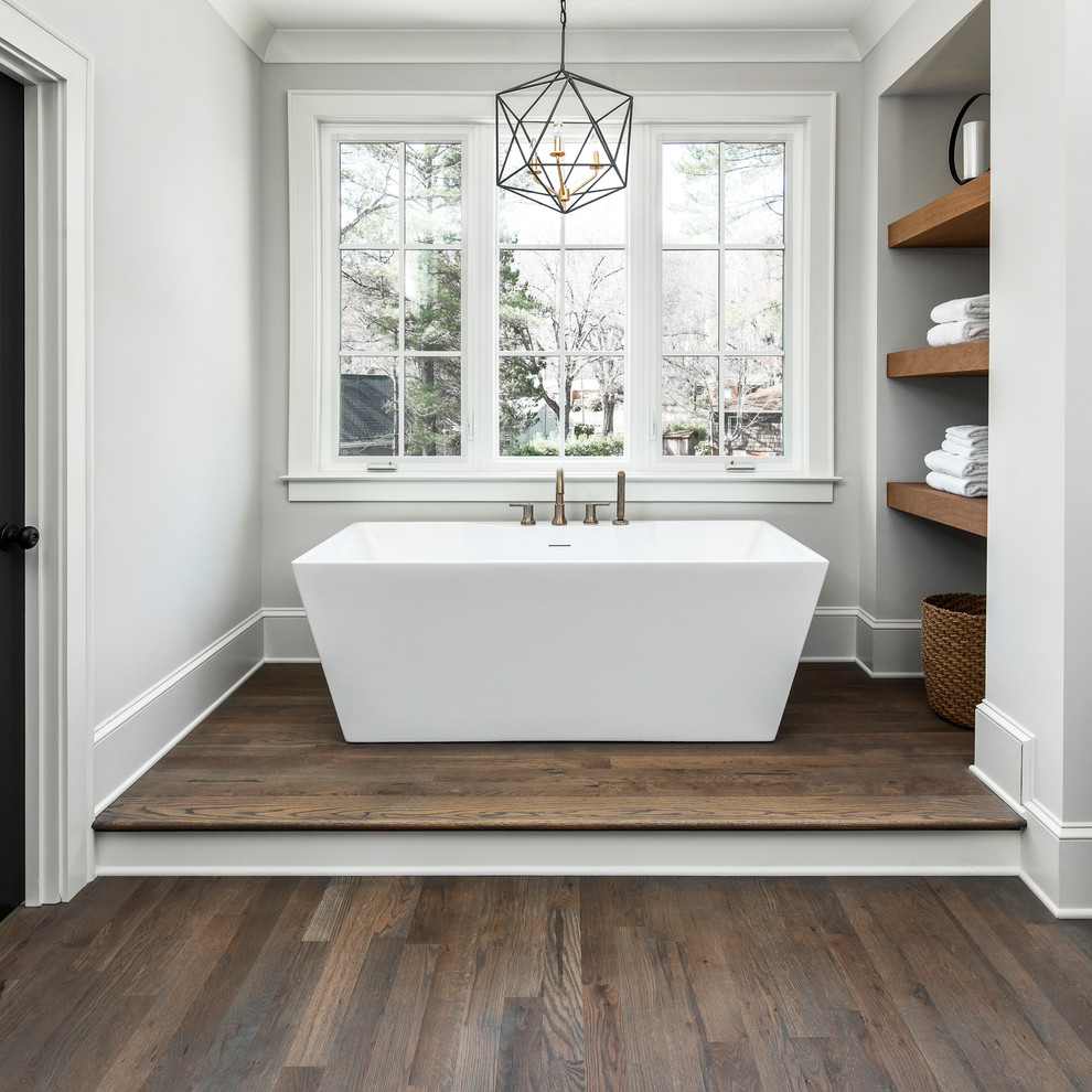 Photo of a large country master bathroom in Charlotte with a freestanding tub, beige walls, medium hardwood floors and brown floor.
