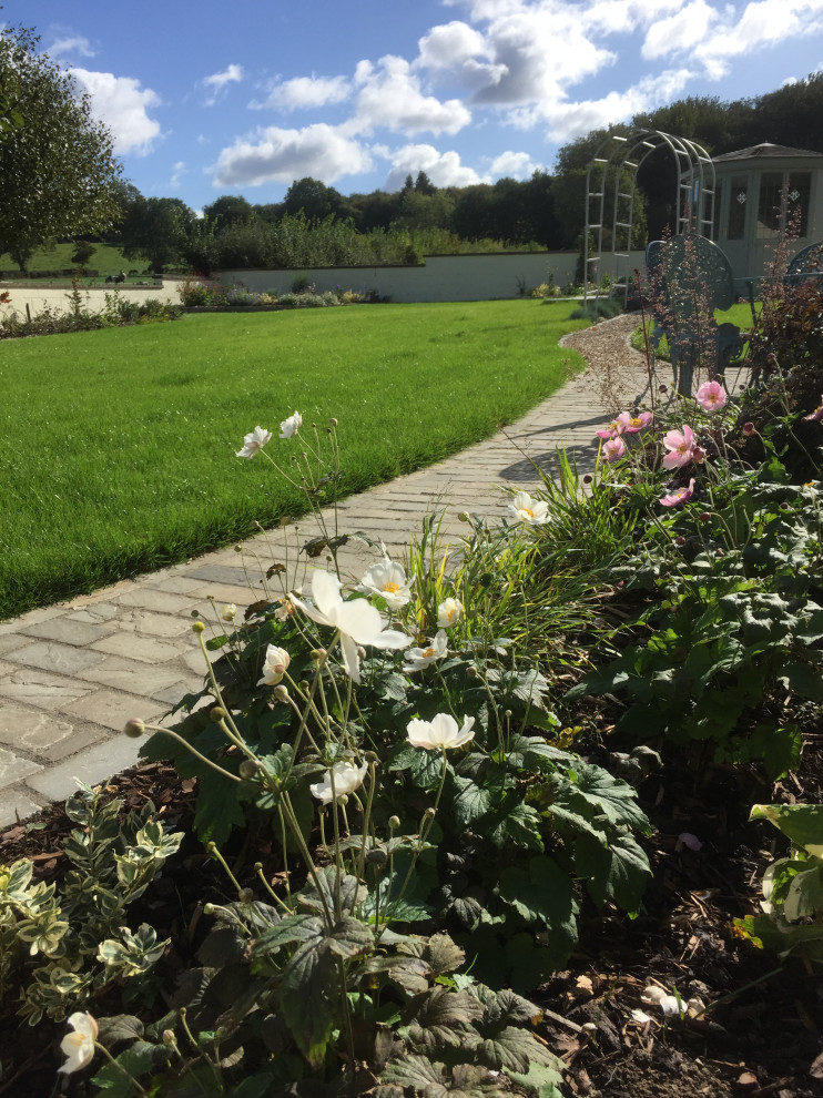 Esempio di un giardino chic esposto in pieno sole di medie dimensioni e dietro casa in estate con pavimentazioni in pietra naturale e recinzione in pietra
