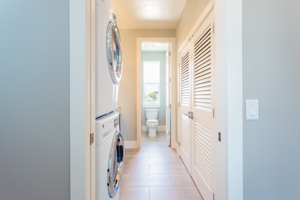 This is an example of a mid-sized transitional single-wall laundry room in Phoenix with an undermount sink, louvered cabinets, granite benchtops, grey walls, ceramic floors and a stacked washer and dryer.