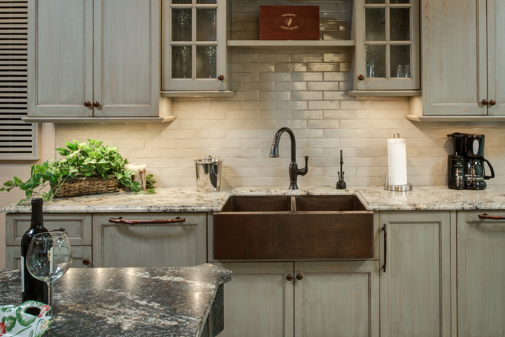 Kitchen - rustic concrete floor kitchen idea with a farmhouse sink, granite countertops, stainless steel appliances, white backsplash, subway tile backsplash, recessed-panel cabinets, beige cabinets and an island