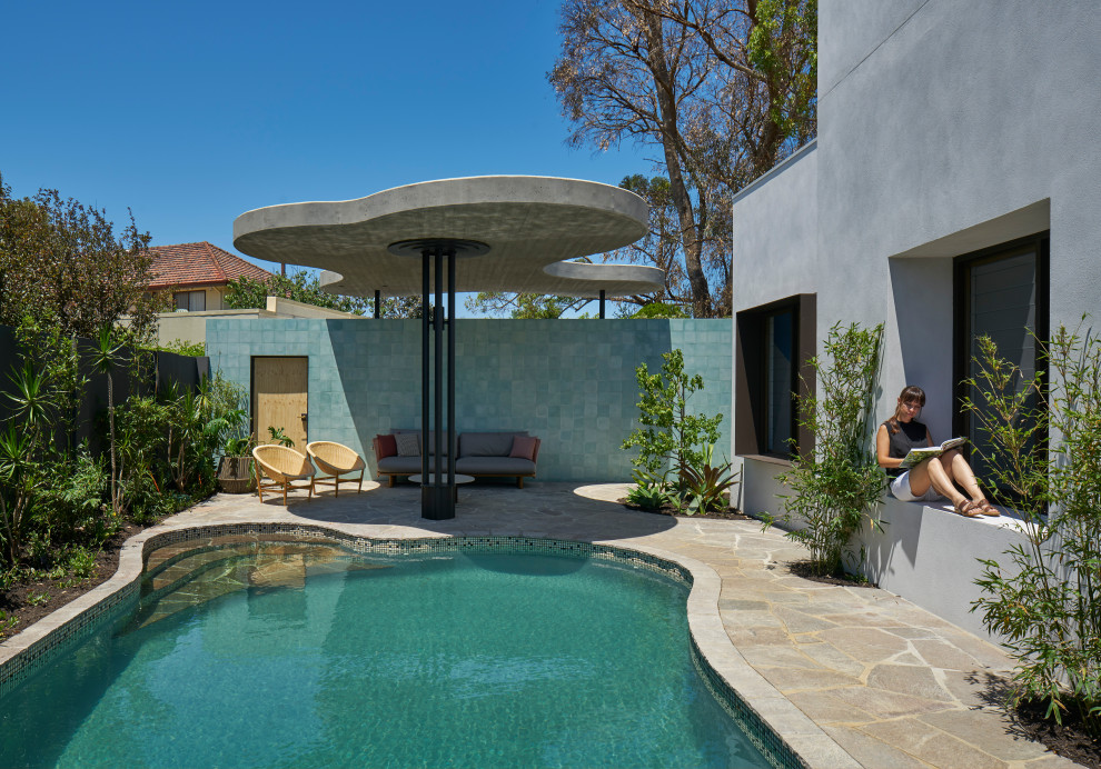 This is an example of a mid-sized midcentury kidney-shaped pool in Perth with natural stone pavers.