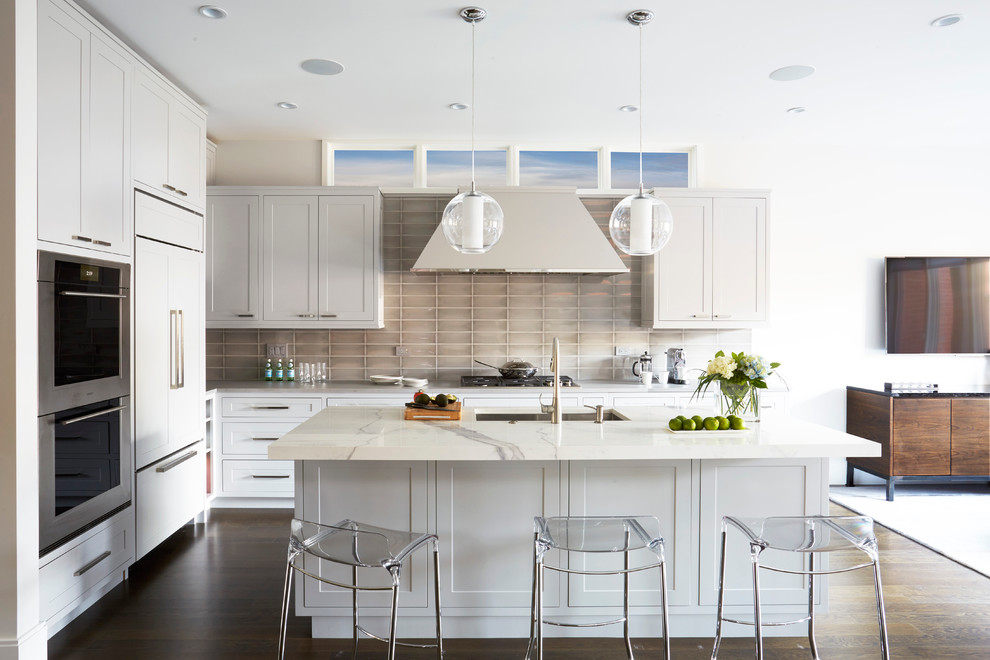 Design ideas for a mid-sized transitional l-shaped eat-in kitchen in Chicago with an undermount sink, shaker cabinets, grey cabinets, onyx benchtops, grey splashback, glass tile splashback, stainless steel appliances, dark hardwood floors and with island.