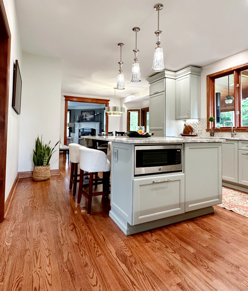 Inspiration for a transitional l-shaped medium tone wood floor eat-in kitchen remodel with shaker cabinets, green cabinets, quartzite countertops, porcelain backsplash, paneled appliances and an island