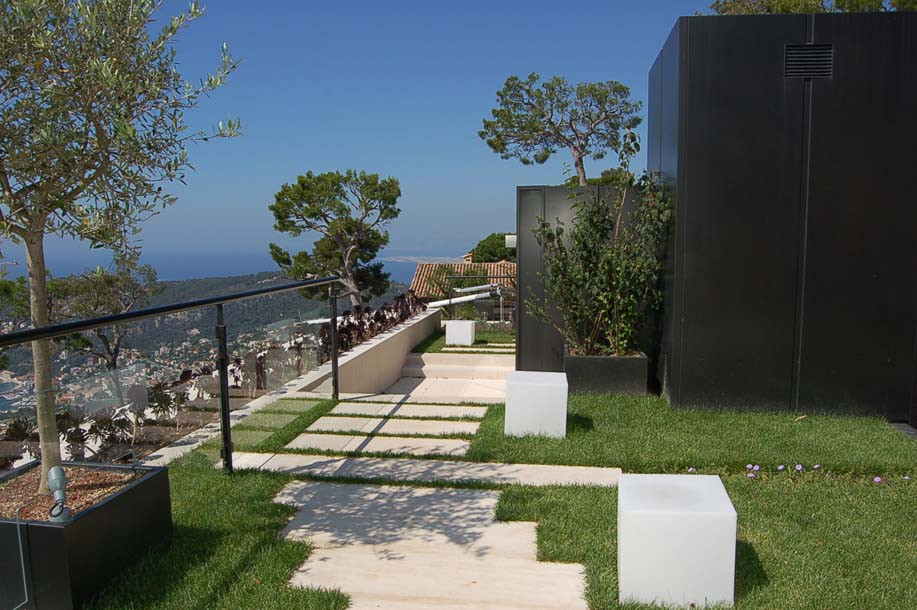 This is an example of a large modern rooftop full sun xeriscape for spring in Nice with natural stone pavers.