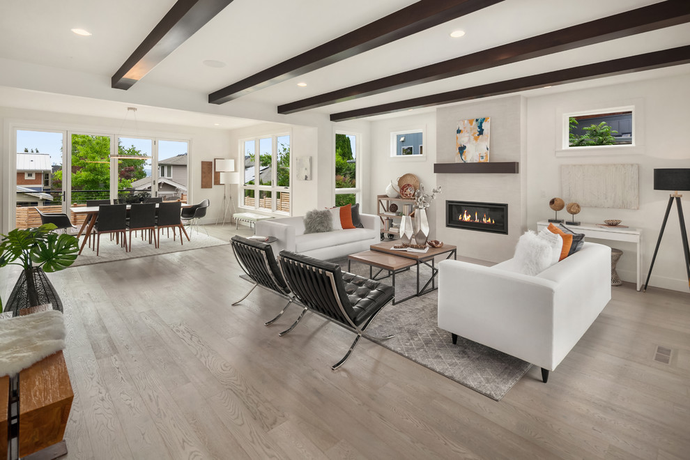 Design ideas for a large midcentury formal open concept living room in Seattle with white walls, light hardwood floors, a standard fireplace, a plaster fireplace surround and beige floor.