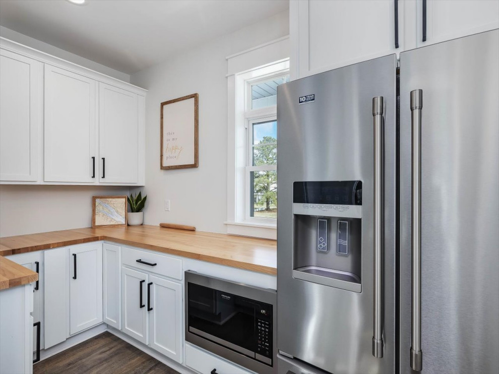 Photo of a small beach style u-shaped kitchen pantry in DC Metro with recessed-panel cabinets, white cabinets, wood benchtops, stainless steel appliances, no island and brown benchtop.
