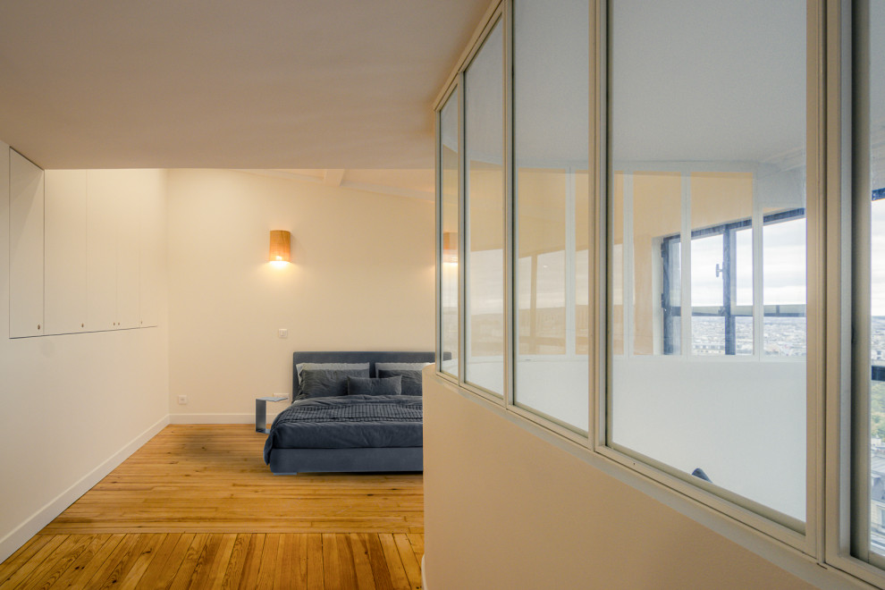 Exemple d'une chambre mansardée ou avec mezzanine beige et blanche moderne avec un mur beige, un sol en bois brun, un sol marron, un plafond décaissé et verrière.