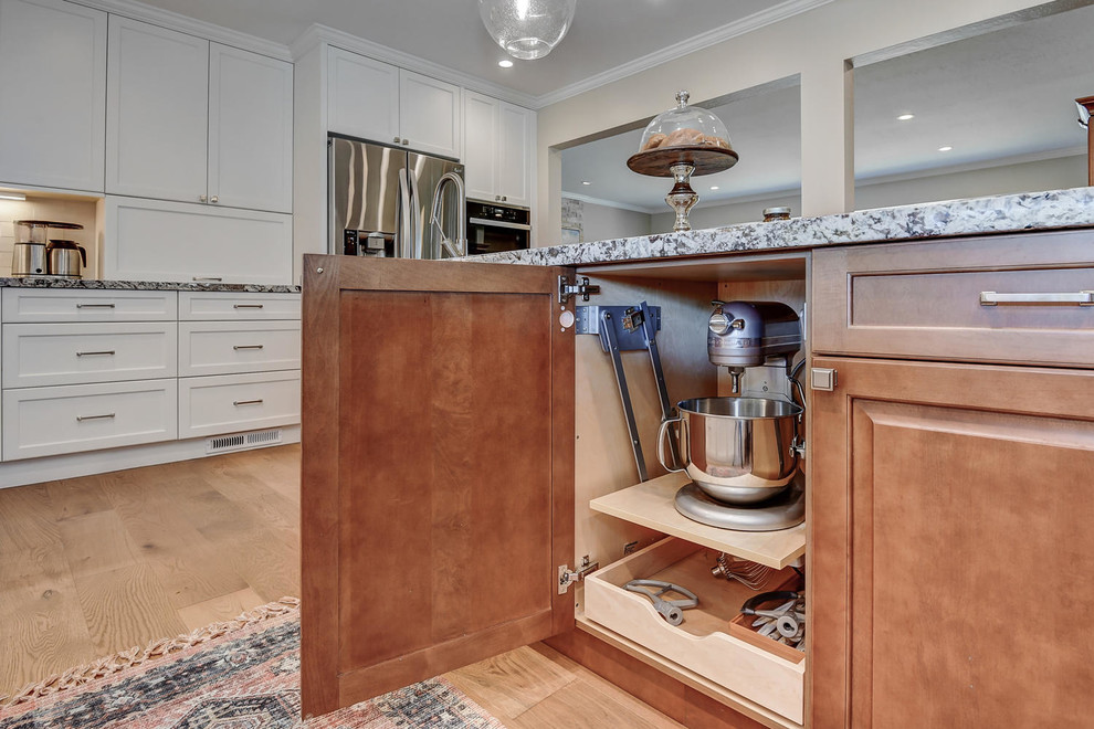 Photo of a large contemporary single-wall eat-in kitchen in San Francisco with a double-bowl sink, shaker cabinets, white cabinets, granite benchtops, stainless steel appliances, medium hardwood floors, with island, brown floor and multi-coloured benchtop.