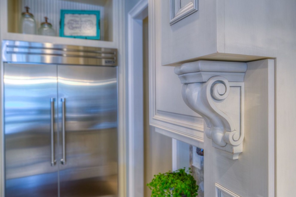 Inspiration for a mid-sized transitional l-shaped light wood floor enclosed kitchen remodel in Orlando with an undermount sink, recessed-panel cabinets, white cabinets, marble countertops, white backsplash, stainless steel appliances and an island