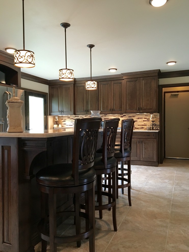 This is an example of a mid-sized traditional l-shaped eat-in kitchen in New York with raised-panel cabinets, dark wood cabinets, ceramic floors, with island, an undermount sink, solid surface benchtops, beige splashback, matchstick tile splashback and stainless steel appliances.