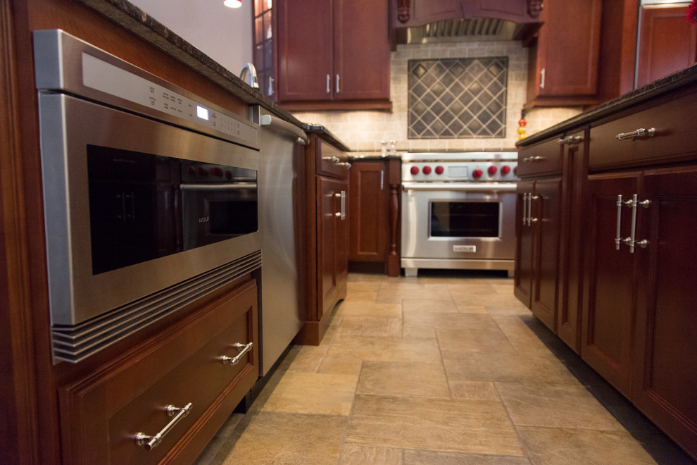Inspiration for a large timeless u-shaped travertine floor eat-in kitchen remodel in Providence with recessed-panel cabinets, dark wood cabinets, granite countertops, beige backsplash, ceramic backsplash, paneled appliances and an island