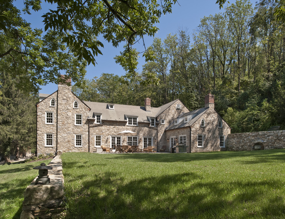 This is an example of a large country three-storey brown house exterior in Philadelphia with stone veneer, a gable roof and a shingle roof.