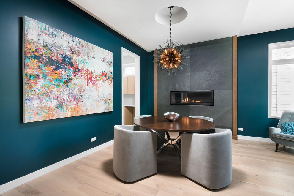 Photo of a mid-sized contemporary dining room in Chicago with blue walls, light hardwood floors, a ribbon fireplace and a tile fireplace surround.