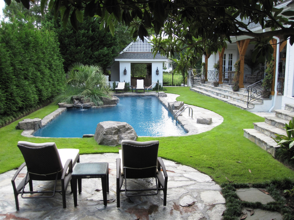 Aménagement d'un piscine avec aménagement paysager arrière avec des pavés en pierre naturelle.