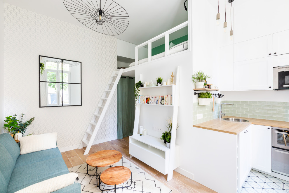 Стильный дизайн: маленькая открытая, объединенная гостиная комната в скандинавском стиле с белыми стенами, светлым паркетным полом, телевизором на стене, бежевым полом и обоями на стенах для на участке и в саду - последний тренд