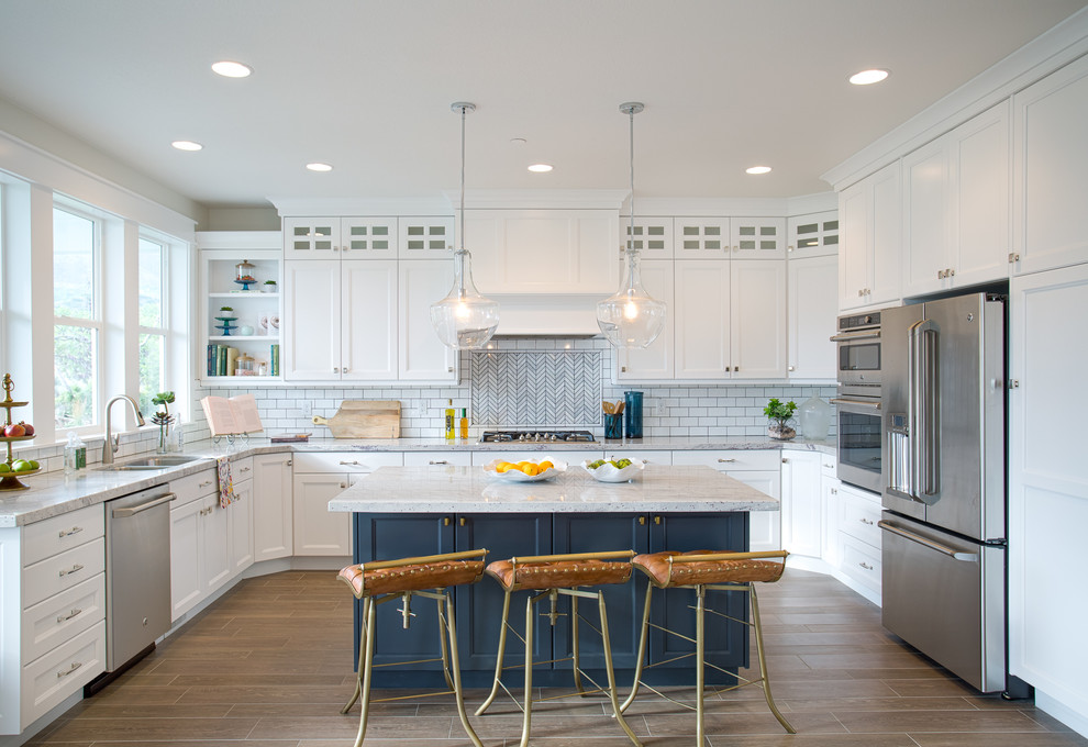 Inspiration for a transitional u-shaped kitchen in Salt Lake City with a double-bowl sink, shaker cabinets, white cabinets, white splashback, subway tile splashback, stainless steel appliances and with island.