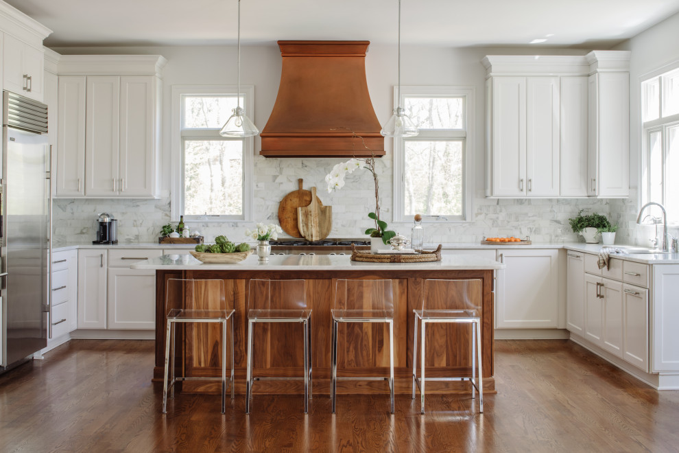 Inspiration for a country u-shaped kitchen in DC Metro with an undermount sink, shaker cabinets, white cabinets, white splashback, stainless steel appliances, medium hardwood floors, with island, brown floor and white benchtop.