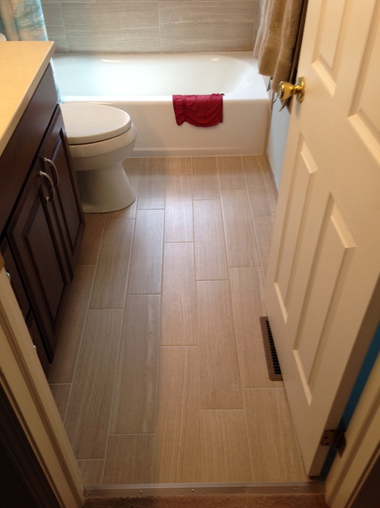 Design ideas for a small transitional kids bathroom in Chicago with raised-panel cabinets, dark wood cabinets, an alcove tub, a two-piece toilet, beige tile, porcelain tile, porcelain floors, an undermount sink and engineered quartz benchtops.