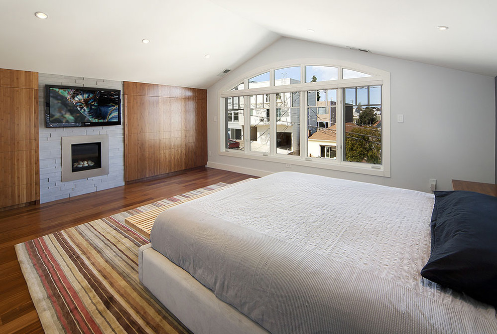 Photo of a large contemporary master bedroom in San Francisco with white walls, medium hardwood floors, a standard fireplace and a stone fireplace surround.