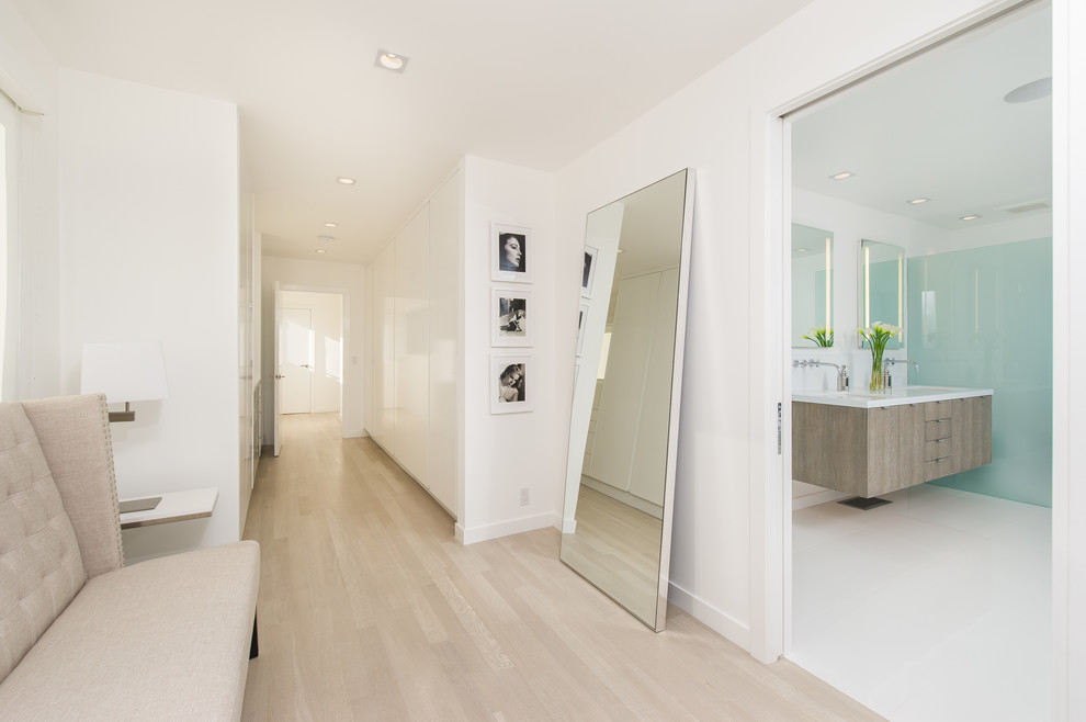 This is an example of a contemporary hallway in Los Angeles with white walls, light hardwood floors and beige floor.