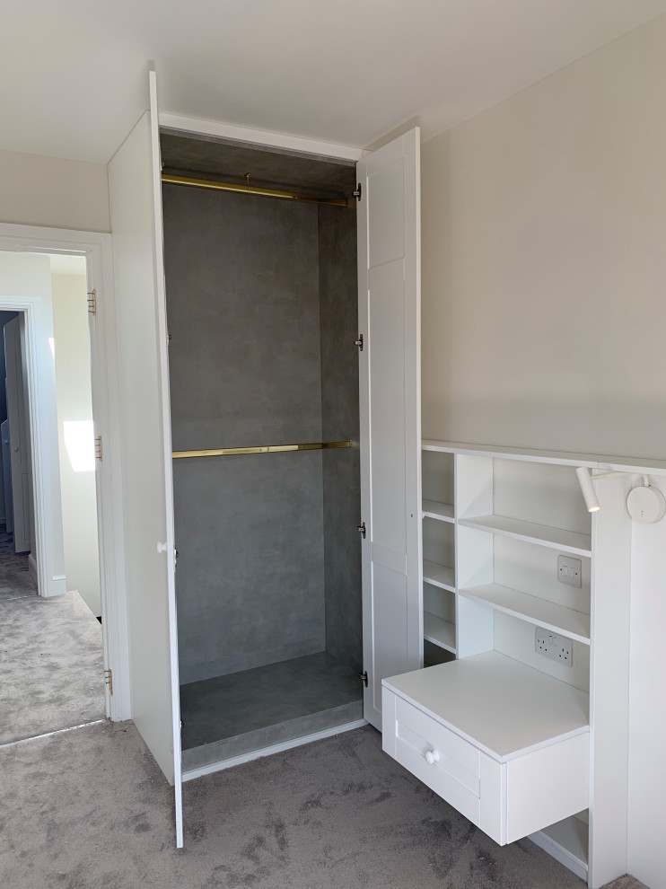 Photo of a medium sized modern built-in wardrobe in London with shaker cabinets, white cabinets, carpet and grey floors.