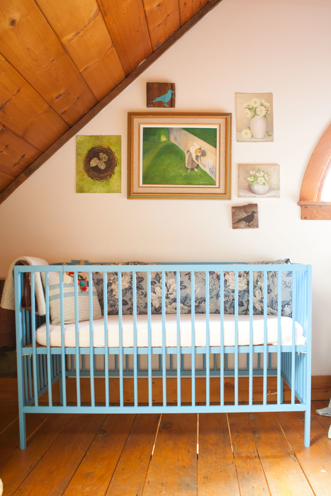 This is an example of a country gender-neutral nursery in Burlington with white walls, medium hardwood floors and orange floor.