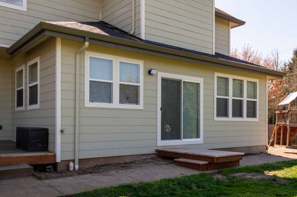 Cette image montre une façade de maison verte design en panneau de béton fibré et bardage à clin de taille moyenne et à un étage avec un toit à quatre pans, un toit en tuile et un toit gris.