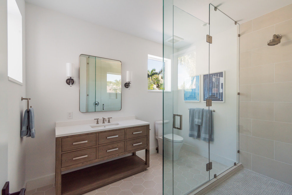 Large beach style 3/4 bathroom in Miami with flat-panel cabinets, medium wood cabinets, a corner shower, beige tile, porcelain tile, white walls, porcelain floors, an undermount sink, beige floor, a hinged shower door and turquoise benchtops.