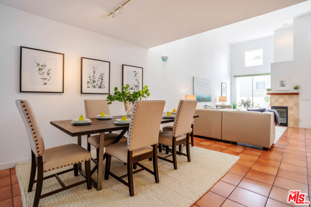 Esempio di una sala da pranzo aperta verso il soggiorno design di medie dimensioni con pareti bianche, pavimento in terracotta e pavimento arancione