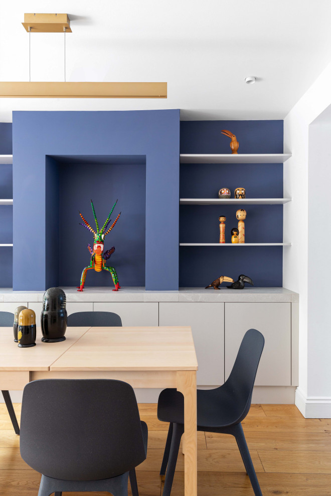 Immagine di una grande sala da pranzo aperta verso il soggiorno design con pareti blu e pavimento in legno massello medio