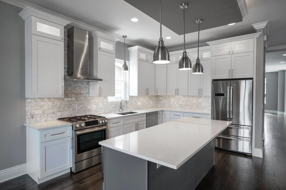 Inspiration for a mid-sized transitional medium tone wood floor and brown floor kitchen remodel in Chicago with an undermount sink, shaker cabinets, white cabinets, quartz countertops, gray backsplash, subway tile backsplash, stainless steel appliances and an island